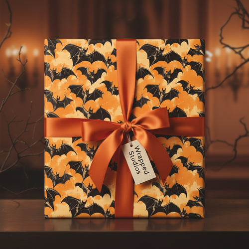 Square gift wrapped in Halloween bat wrapping paper with orange satin ribbon and bow.