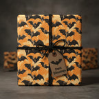 Square gift wrapped in bat-print Halloween wrapping paper with black string and tag.