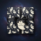 Wrapped gift box with black satin ribbon and ghost pattern Halloween wrapping paper.