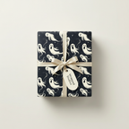 Spooky Halloween gift wrapped in ghost-patterned wrapping paper with a cream ribbon and tag.