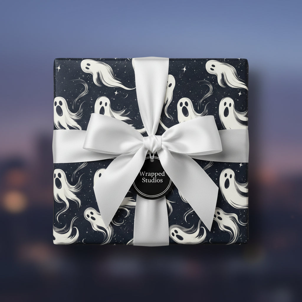 Square gift wrapped in ghost print Halloween wrapping paper, tied with a white satin bow.