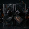 Elegant black gift box wrapped in spiderweb luxury wrapping paper with satin bow and gift tag.