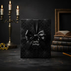 Elegant black gift wrapped in spiderweb "Spooky Greetings" Halloween wrapping paper with a satin bow.
