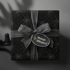 Elegant black gift wrapped in spiderweb Halloween wrapping paper with sheer gray ribbon.