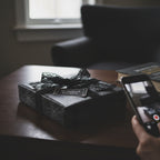 Elegant black spiderweb wrapping paper with a lace ribbon bow and "Wrapped Studios" tag.