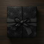 Square gift wrapped in black spiderweb paper with gray ribbon and twine bow.