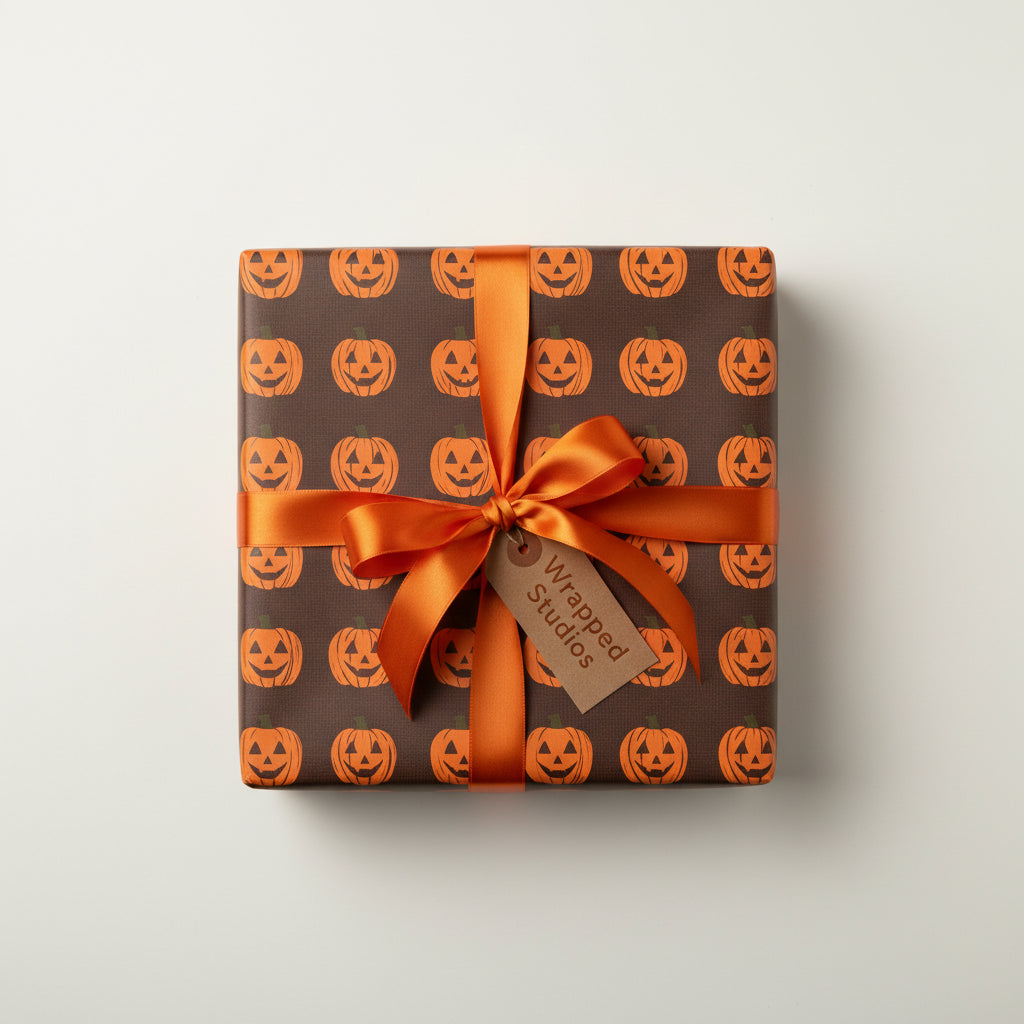 Square gift wrapped in brown Halloween wrapping paper with jack-o'-lanterns and tied with an orange ribbon.