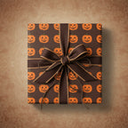 Square gift wrapped in brown Halloween wrapping paper with orange jack-o-lanterns and a brown ribbon.