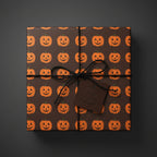 Square gift box with brown Halloween wrapping paper and smiling pumpkin pattern, tied with black string and a "Happy Halloween" tag.