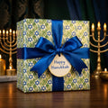 Luxury Hanukkah gift wrap with Star of David pattern, blue satin ribbon, and tag by Wrapped Studios.