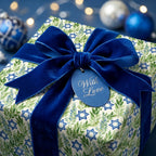 Hanukkah wrapping paper with Star of David pattern, blue velvet bow, and gift tag by Wrapped Studios.