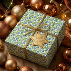 Hanukkah wrapping paper with blue Star of David and green leaves, tied with gold ribbon by Wrapped Studios.