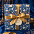 Blue Hanukkah wrapping paper with gold satin bow and Happy Hanukkah tag by Wrapped Studios.