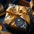 Luxury Hanukkah wrapping paper in blue and gold Star of David print with a gold bow by Wrapped Studios.