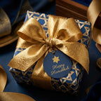 Luxury Hanukkah wrapping paper in blue and gold Star of David print with a gold bow by Wrapped Studios.