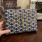 Blue and gold Star of David Hanukkah wrapping paper with a gold string bow, by Wrapped Studios.