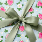 Cute watermelon wrapping paper with a sage green ribbon bow, perfect for summer birthdays by Wrapped Studios.