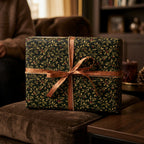 Elegant Christmas gift wrap with holly leaf and berry pattern, tied with a shimmering copper ribbon.