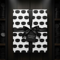 Wrapped Studios hockey puck pattern wrapping paper with a sleek black satin ribbon bow.
