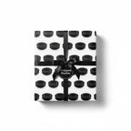 Wrapped gift in black hockey puck print wrapping paper and tied with a black satin ribbon.