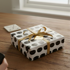 Unique black and white hockey puck patterned wrapping paper with gold ribbon and gift tag.