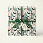 Dog Christmas wrapping paper with pointer dogs and trees, tied with a green ribbon by Wrapped Studios.