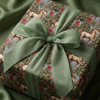 Vintage horse Christmas wrapping paper with sage green ribbon on a gift box by Wrapped Studios.