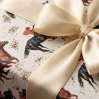 Equestrian wrapping paper with vintage horse racing pattern and cream satin bow by Wrapped Studios.