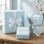 Elegant light blue wrapping paper on gift boxes tied with white and silver satin ribbon bows.