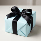 Light blue gift box wrapped with black satin ribbon and bow for birthday or special occasion.