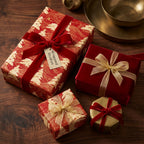 Elegant red and gold Christmas wrapping paper with luxury velvet ribbons on a wood table by Wrapped Studios.