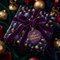 Luxury Christmas wrapping paper with purple ornament pattern and velvet bow by Wrapped Studios.