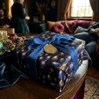 Luxury Christmas gift wrap in dark purple and blue with blue silk bow and gold Joy tag by Wrapped Studios.