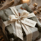 Rustic gray luxury wrapping paper with a cream linen bow and "With Love" tag by Wrapped Studios.