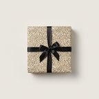 Beige luxury gift wrap with minimalist black pattern and satin bow for birthday or special occasion.
