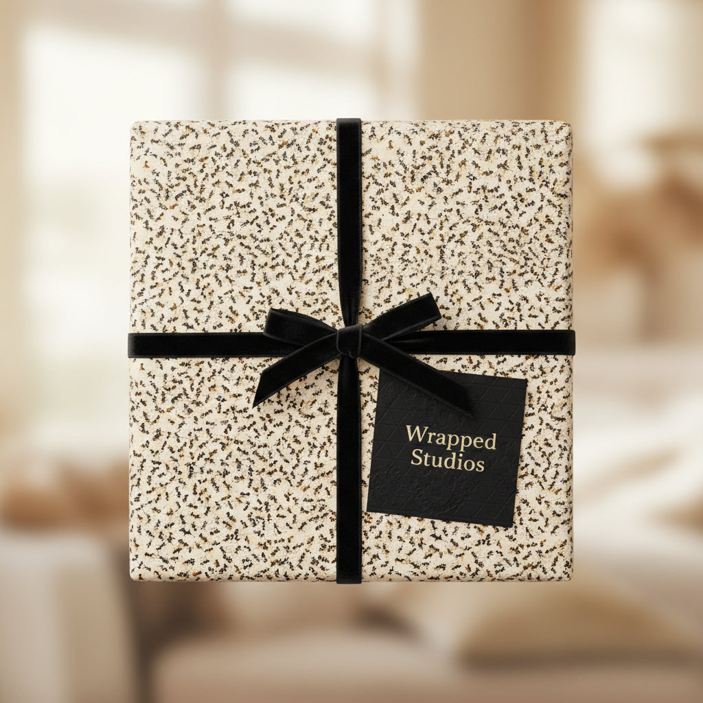 Elegant square gift wrapped in modern floral wrapping paper with black velvet ribbon and bow.