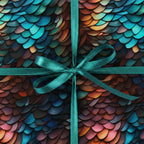 Teal ribbon adorns a gift wrapped in a modern, scale-patterned luxury gift wrap with blue, orange, and brown hues.