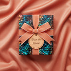 Teal scale pattern luxury gift wrap with peach ribbon & "From the Heart" tag, set on silky peach fabric.