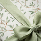 Sage green botanical wrapping paper with a matching fabric ribbon bow by Wrapped Studios.