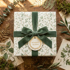 Luxury botanical wrapping paper with a sage green velvet ribbon bow on a rustic wood table by Wrapped Studios.