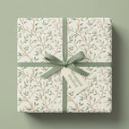 Botanical sage green wrapping paper with a leaf pattern on a gift box with ribbon by Wrapped Studios.