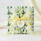 Elegant gift wrapped in lemon-print wrapping paper with yellow ribbon and "A Zesty Treat" tag.