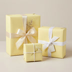 Three gifts wrapped in light yellow paper with ribbon and floral accents, perfect for birthdays or baby showers.