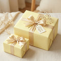 Elegant lemon yellow wrapping paper with gold satin ribbon and bow for birthday, wedding, or baby shower gifts.