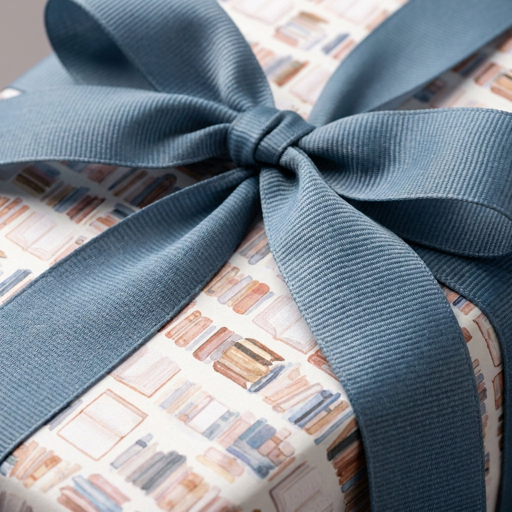 Book lover wrapping paper with watercolor book pattern and dusty blue ribbon by Wrapped Studios.