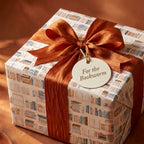 Book lover gift wrap with watercolor books pattern and rust bow by Wrapped Studios.