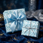 Two presents wrapped in luxury floral wrapping paper with blue ribbons sit on a velvet cloth.
