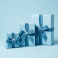 Three light blue gifts wrapped in solid wrapping paper with matching velvet ribbon bows.