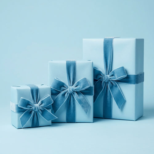 Three light blue gifts wrapped in solid wrapping paper with matching velvet ribbon bows.