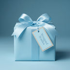 Elegant light blue gift wrap on a square present with a satin ribbon and a tag.